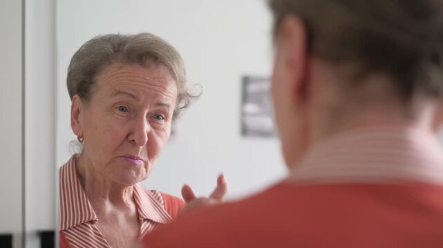 Senior woman talking to herself while looking in the mirror, close-up