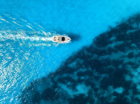 Aerial drone view of beautiful floating boat in blue sea on sunny day in summer. Mallorca island, Spain. Top down view of boat, sea, turquoise water. Travel. Tropical landscape. Yachting. Cruise