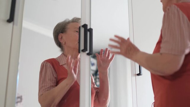 Happy elderly woman dancing and smiling while looking in the mirror