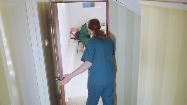 Caregiver checks doorway carefully. Medical staff carefully examine corridor and door before entering. Healthcare professional pauses and surveys surroundings prior to patient room entry