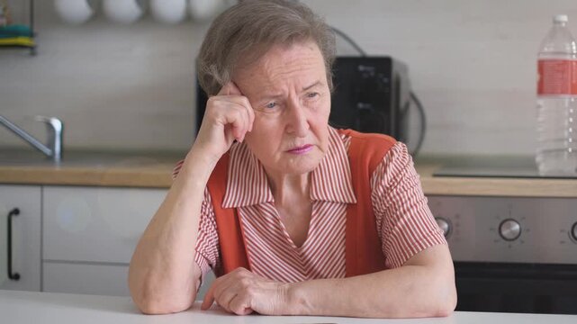Sad pensive elderly woman in the kitchen at home