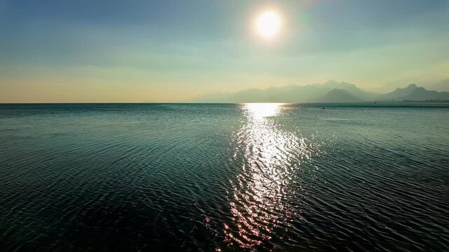 Sparkling mediterranean sea with sun glare reflection and taurus mountains silhouette on horizon antalya.