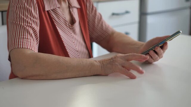 A mature woman taps her fingers on the table while waiting for the call