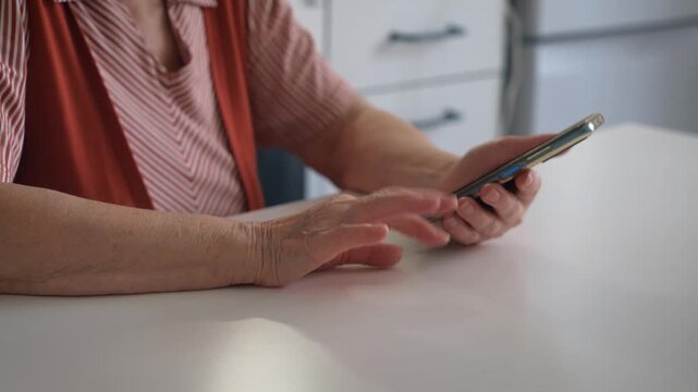 A mature woman taps her fingers on the table while waiting for the call.