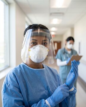 PPE healthcare worker adjusting gloves in a calm hospital corridor