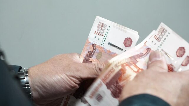 Man counts a bundle of bills for five  thousand Russian rubles at the workplace. Man counts paper, 5000 rubles bills. Russian cash money in male hand. A man holds a wad of money in his hands. Russian.