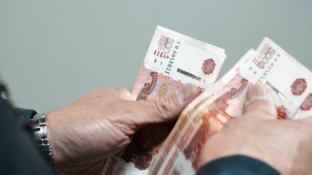 Man counts a bundle of bills for five  thousand Russian rubles at the workplace. Man counts paper, 5000 rubles bills. Russian cash money in male hand. A man holds a wad of money in his hands. Russian.