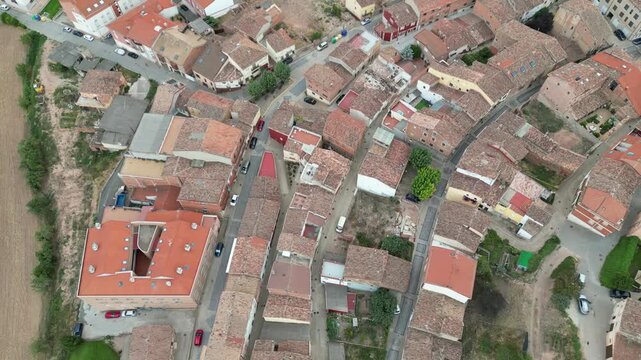 A drone view of winding village streets with red-roofed houses, trees, and fields surrounding the settlement in Camino de Santiago, Navarrete, Spain