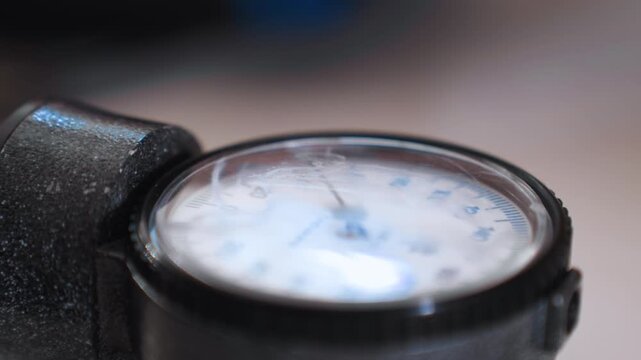 Closeup blood pressure gauge on black cuff home paramedic assesses elderly patient during urgent call, shallow focus, soft ambient light, worn dial, motion blur, tense atmosphere, portable equipment