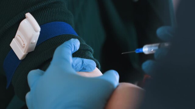 Closeup tourniquet tightened on arm before draw, gloved hands prepare syringe and vial, steady pressure on vein, clinical precision in residence, sample collection for lab, focused emergency care