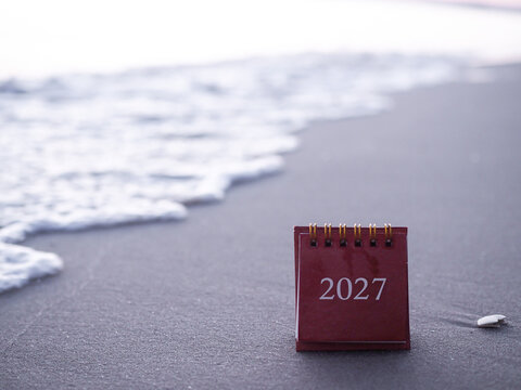 Close up 2027 desk calendar on the beach in the sunset time. Resolution, Goal, Action, Planning, and manage to success business