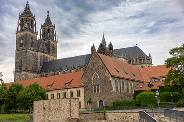 Obraz premium Historic cathedral complex with stone architecture and red tiled roofs under dramatic sky