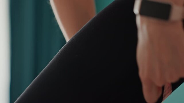 Home rehab thigh assessment using pink tape, woman in black leggings performs clinicalstyle self check in bedroom, focused measurement for recovery and mobility tracking, steady hands, smartwatch