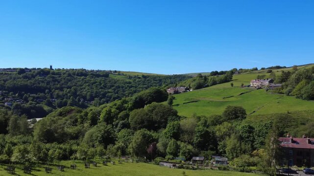 panoramic aerial view showing the villages of heptonstall and old town with the town of hebden bridge visible in the valley surrounded by trees and meadows in summer