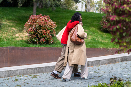 Carefree african american man and woman partners walking in city park hugging and enjoying happiness in relationships, relaxed loving black male and female couple on daily walk outdoors together