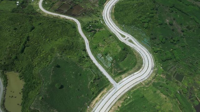 Path Winding Over Lush Landscape. Aerial View Of Curving Path Amidst Rich Foliage And Wetlands. Picture Taken From Above Showing Looped Highway Surrounded By Dense Woodland And Marshes,Lombok
