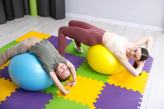 Little girl and trainer exercising with fitness balls indoors