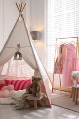 Cute wigwam, clothes, cushions and toy in stylish child's room © New Africa
