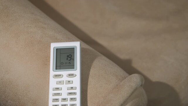 Man finger change conditioner temperature. View of man finger press the button on the remote controller to feel comfortable temperature in the room