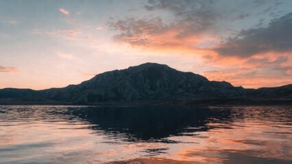 Fototapeta premium Mountain silhouette reflects in calm, golden waters