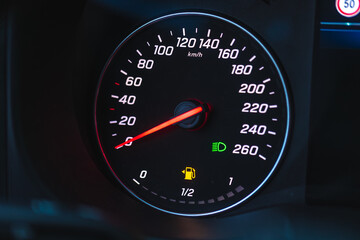Fototapeta premium Modern car dashboard speedometer at night. Driver monitors driving speed and low fuel warning light.