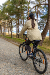 Fototapeta premium Woman cycling on forest path. Active seaside recreation scene
