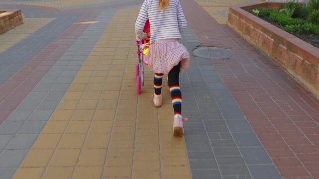Little beautiful girl rolls toy baby carriage with doll