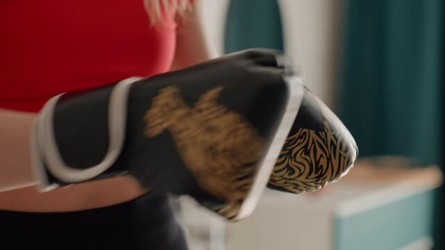 White woman boxing glove closeups showing tattooed midriff, gold patterned gloves and strap adjustments, intimate preparation in bedroom, textured leather detail, focused hands tightening wrist