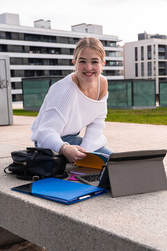 Young woman student smiling studying on campus outdoors
