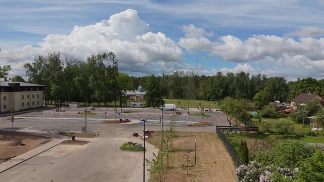 Urban landscape transformation showing parking lot development with trees, buildings, and blue sky in a vibrant outdoor setting