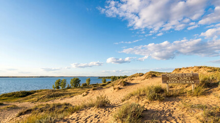 Fototapeta premium Expansive Canadian landscapes with serene sandy dunes gently meeting the tranquil waters under a vast blue sky, offering a peaceful natural escape