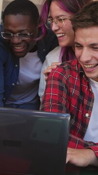 Group of diverse students celebrating success on laptop