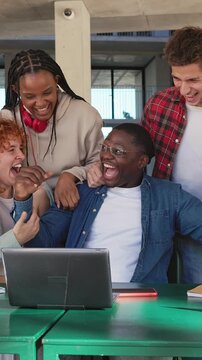 Group of excited students celebrating success with laptop