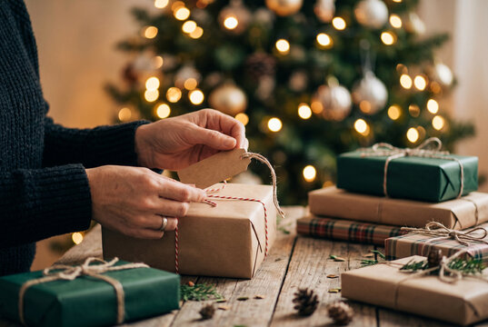 Person attaching blank gift tag to wrapped christmas present