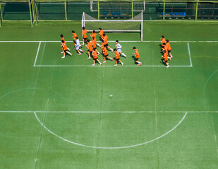 Aerial view of children in orange jerseys running across the soccer field during soccer practice at a sports park in Wuhan, China. © 晨啸 周