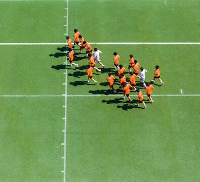 Aerial view of children in orange jerseys running across the soccer field during soccer practice at a sports park in Wuhan, China.