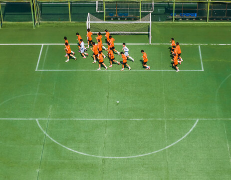 Aerial view of children in orange jerseys running across the soccer field during soccer practice at a sports park in Wuhan, China.