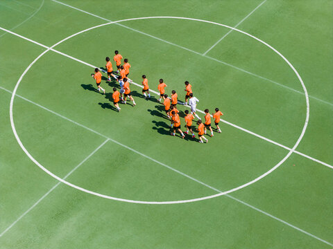Aerial view of children in orange jerseys running across the soccer field during soccer practice at a sports park in Wuhan, China.