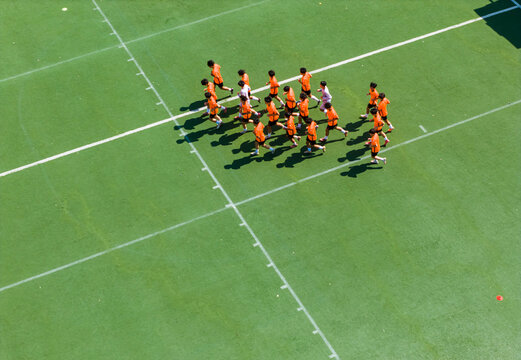 Aerial view of children in orange jerseys running across the soccer field during soccer practice at a sports park in Wuhan, China.