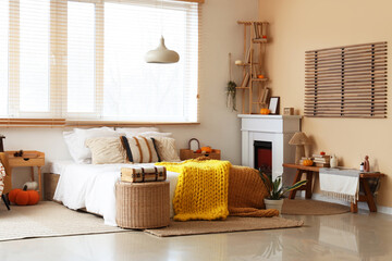 Obraz premium Interior of cozy bedroom with wicker table, fireplace and autumn decor