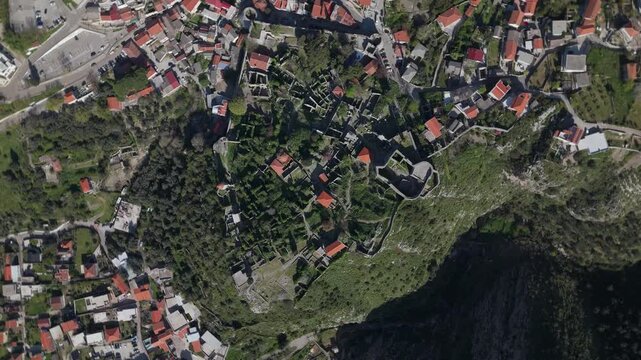 Stari Bar ruins sit on terraced slopes above coastal hinterland with ancient stone walls, narrow paths, olive groves, and clustered red tiled roofs conveying historic Montenegrin village character and