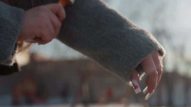 Cleaning clothing quickly. Individual efficiently removing lint from clothing against soft outdoor glow. Person performs fast lint removal routine on their coat in casual street environment