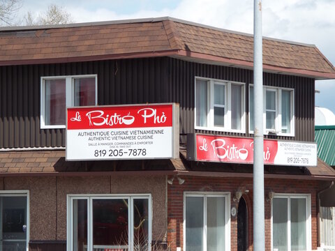 Gatineau, Quebec, Canada &ndash; May 7, 2026: A red signs for "Le Bistro Ph&ocirc;" Vietnamese restaurant are mounted on a two-story brown and brick building at 62 Boul Saint-Raymond.
