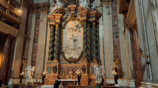A breathtaking interior view of Sant Andrea della Valle in Rome, showcasing magnificent golden ornaments, high marble columns, and exquisite Baroque frescoes painted on the grand church ceiling.

