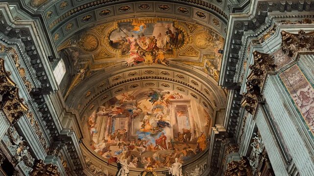 A breathtaking interior view of Sant Andrea della Valle in Rome, showcasing magnificent golden ornaments, high marble columns, and exquisite Baroque frescoes painted on the grand church ceiling.

