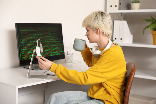 Female programmer with coffee and tablet computer working in office