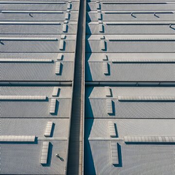 High-angle drone perspective of industrial warehouse rooftops featuring a symmetrical grid pattern with clean geometric textures and lines, texture, roof, architecture