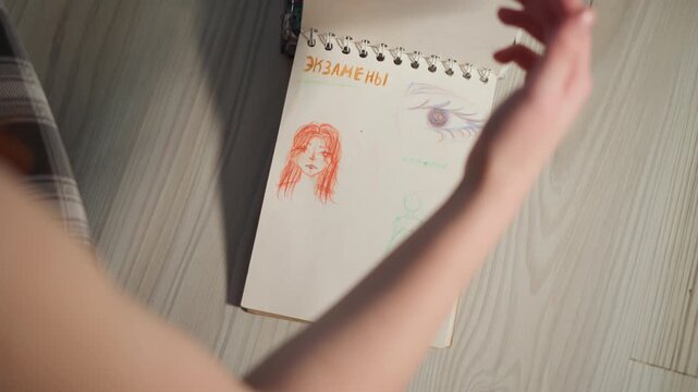 Artist flipping sketchbook pages, sequential reveal of dress studies in ink and color, hands and arms in frame, playful annotations in marker, tabletop studio aesthetic, creative process captured.