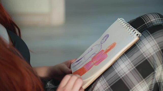 Woman draws in soft daylight. Artistic woman with red hair captures intimate couple in diary mood. Woman with vibrant red hair creates gentle sketch of couple amid bright daylight atmosphere