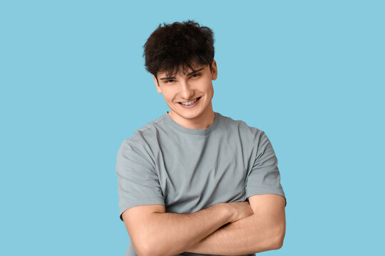 Smiling young man with dental braces on blue background